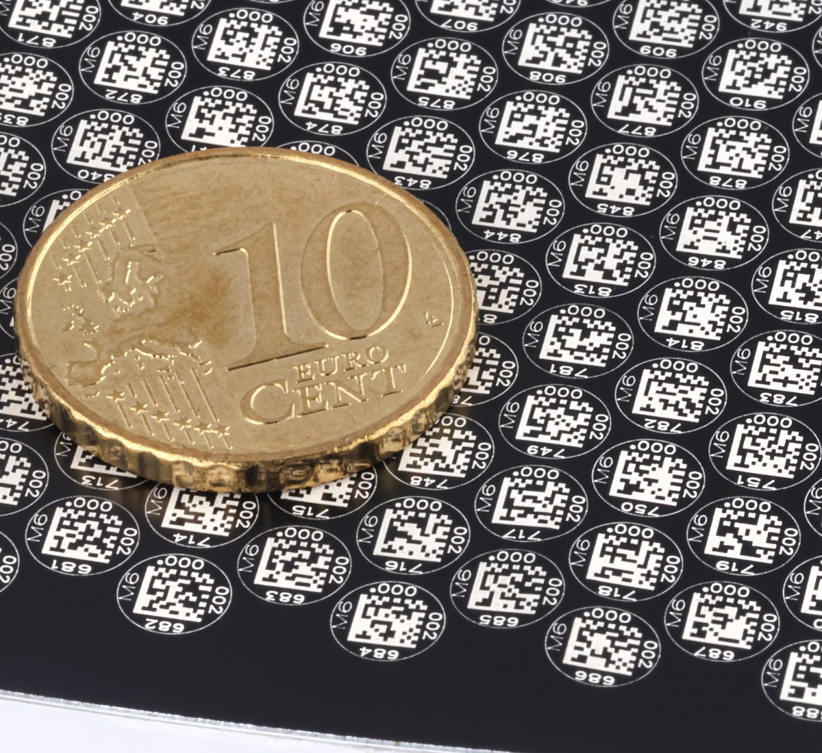 Pastilles en polymères multicouches avec DataMatrix miniature, comparées à une pièce de 10 centimes
