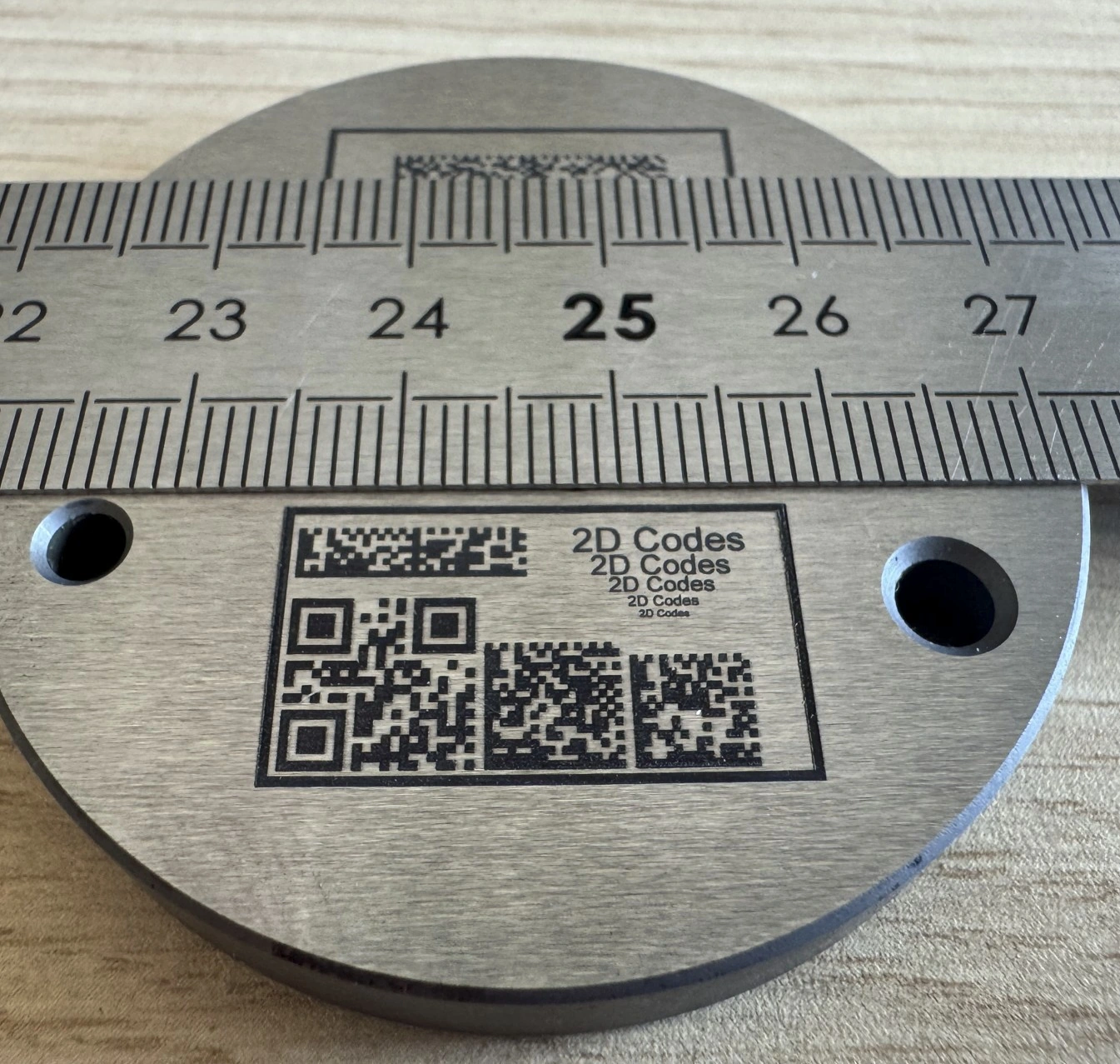 Ansicht eines Horlogerie‑Posage mit Texten, Motiven und 2D‑Codes, schwarz markiert mit UV‑Laser 5 W