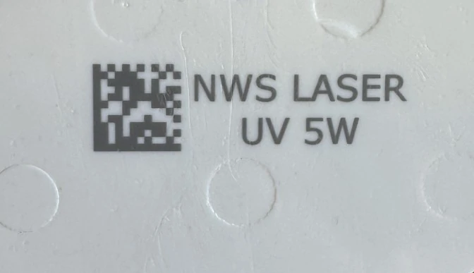 Kod 2D i identyfikacja tekstowa oznakowane laserem UV na jasnym elemencie z tworzywa kompozytowego